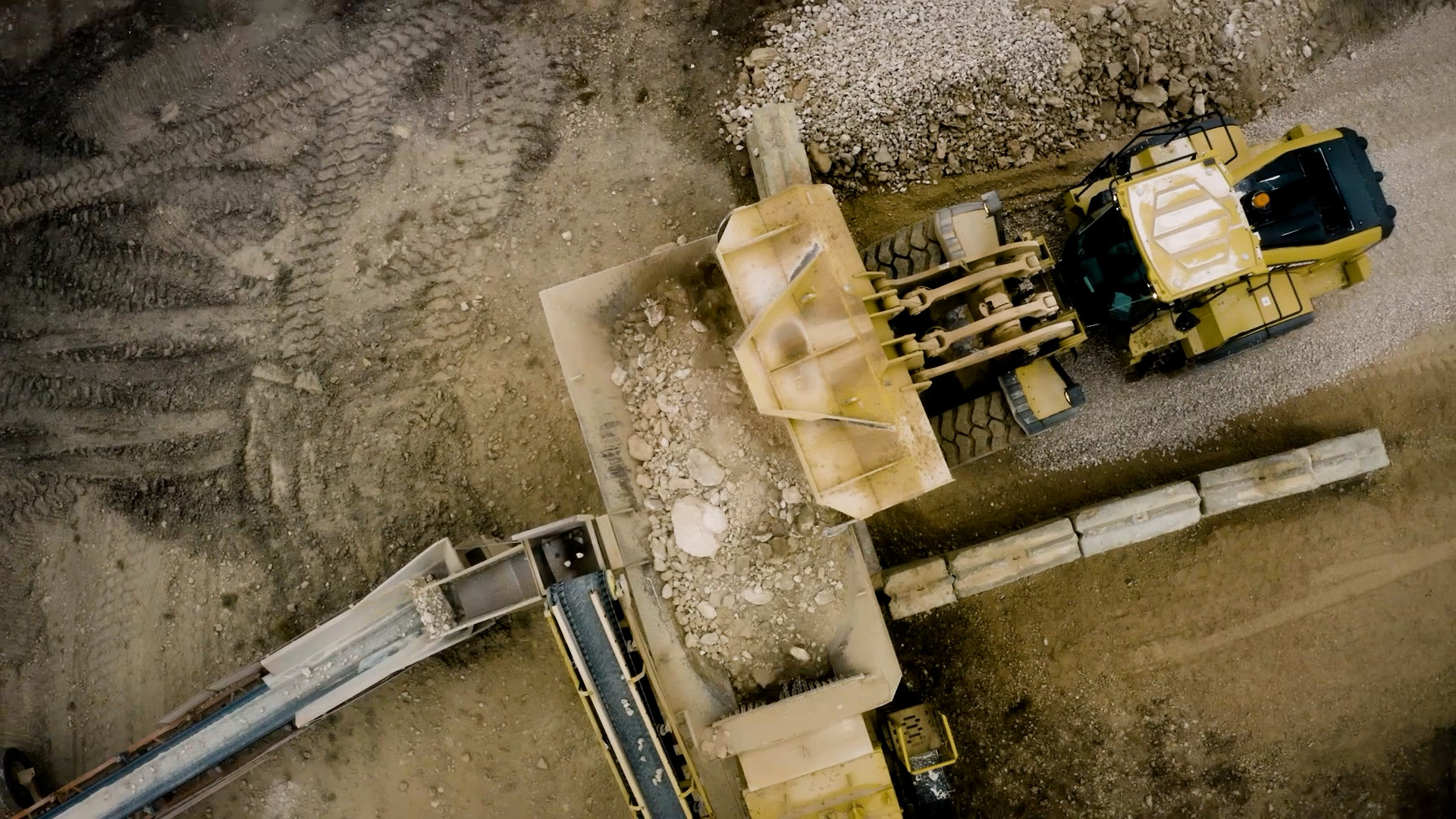 Drone footage of a loader dumping rock into a crusher
